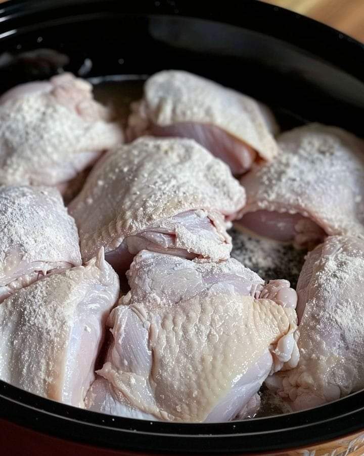 Coat chicken in flour and toss in slow cooker